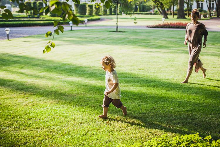 chłopiec z mamą biegną po trawniku w parku