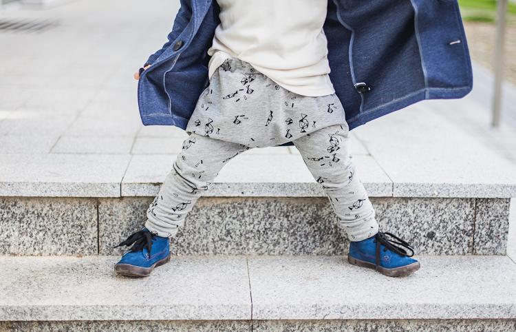 chłopiec w szarych spodniach baggy z czarnym printem i butach z niebieskiego zamszu