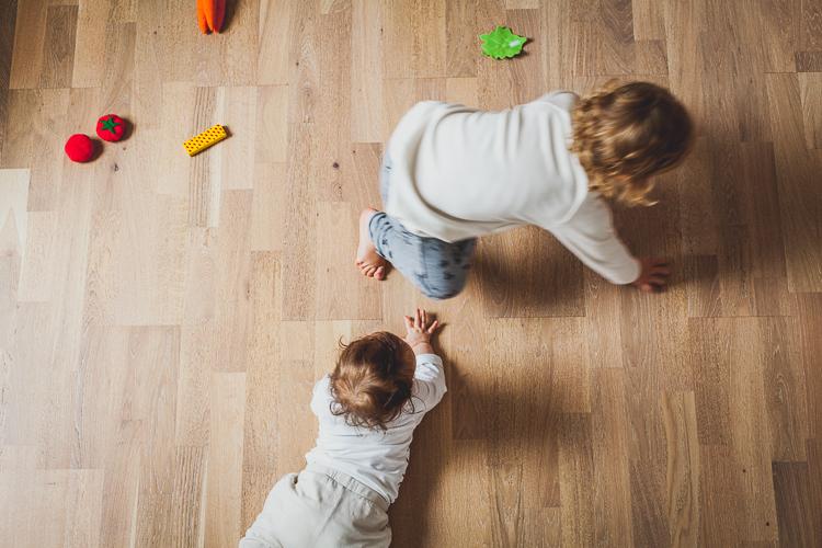 raczkujące dzieci bawią się na drewnianej podłodze mieszkania
