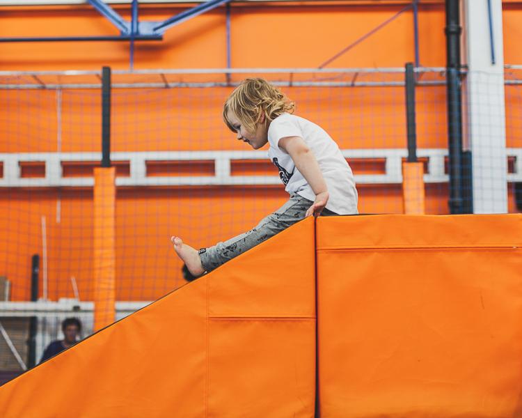 mały chłopiec bawi się na torze przeszkód na trampolinach jump city