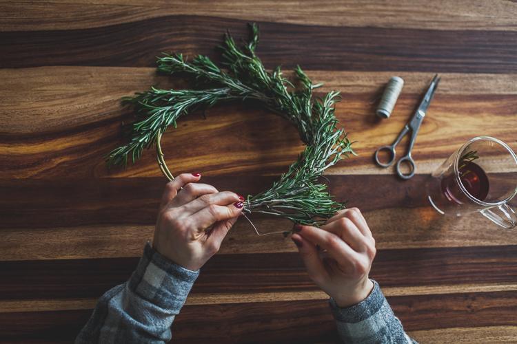 girl fixing rosemary with a stich to a base ring made of willow twig